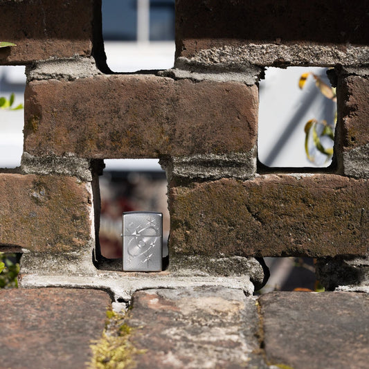 Lifestyle image of Zippo Atomic Cosmos Design Satin Chrome Windproof Lighter standing in a gap of a brick wall.