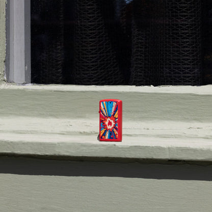 Lifestyle image of Zippo Comic Blast Design Slim Red Matte Windproof Lighter standing on a painted window ledge.