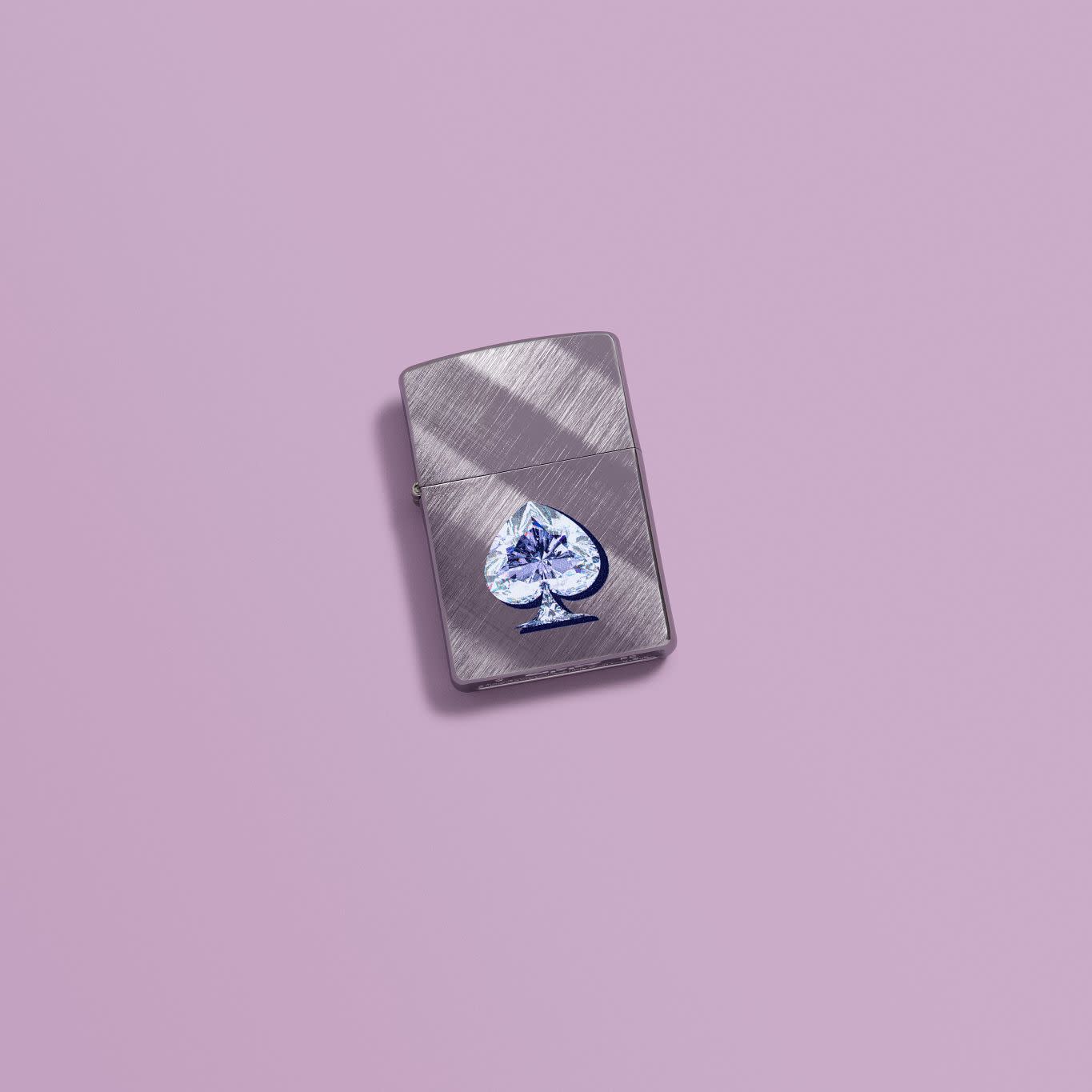Lifestyle image of Zippo Gleaming Spade Design Diagonal Weave Windproof Lighter in a purple scene.